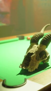 A skull rests on a green pool table. The setting is a dimly lit room with colorful decorations. The focus is on the skull and the texture of the table surface.