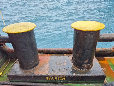 Close-up of bollards with &ldquo;SWL 8 TON&rdquo; marking on a weathered ship deck.