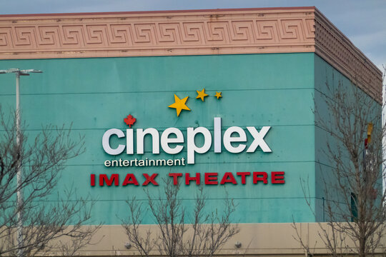 Calgary, Alberta, Canada. May 05, 2026. Cineplex Entertainment IMAX theatre exterior with teal facade and signage, low-angle urban view under cloudy sky
