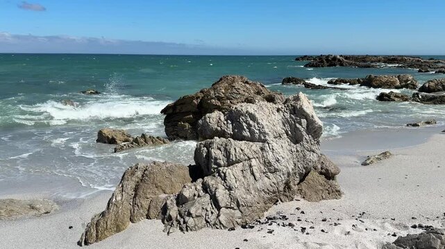 Hermanus coastline in South Africa with ocean waves, sandy beach and deep blue sky, beautiful summer landscape with relaxed holiday atmosphere.