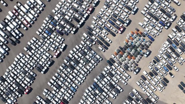 Aerial top-down view showing thousands of new cars neatly parked in a huge lot, a powerful symbol of mass production, automotive industry, and global supply chain logistics