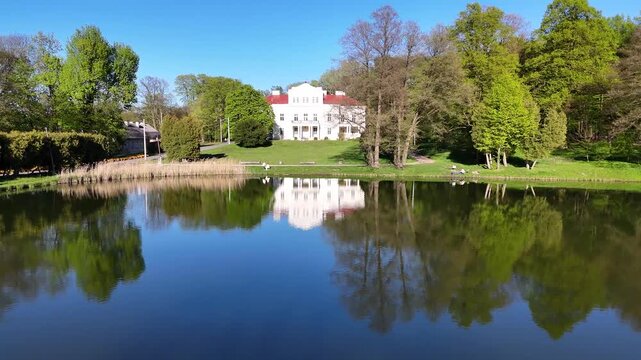 Drone shot of Raczynski Palace reflected in Irydion Pond, Poland