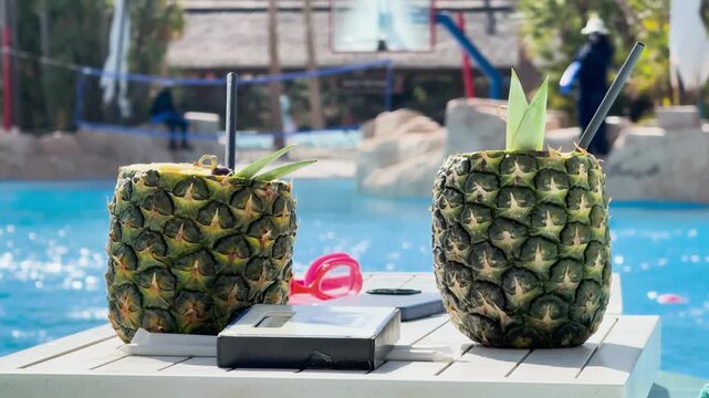 Tropical pineapple cocktails by swimming pool, summer beverages