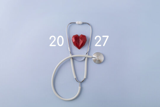 White stethoscope and numbers 2027 on pastel blue background. The concept of health care in the New Year. Selective focus, copy space