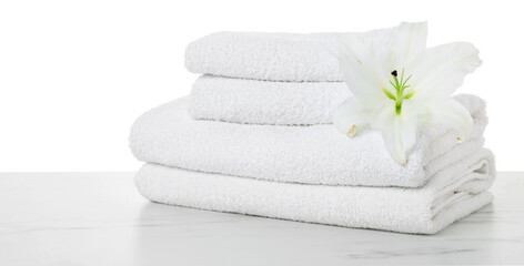 Naklejka premium Stacked terry towels and lily flower on marble table against white background