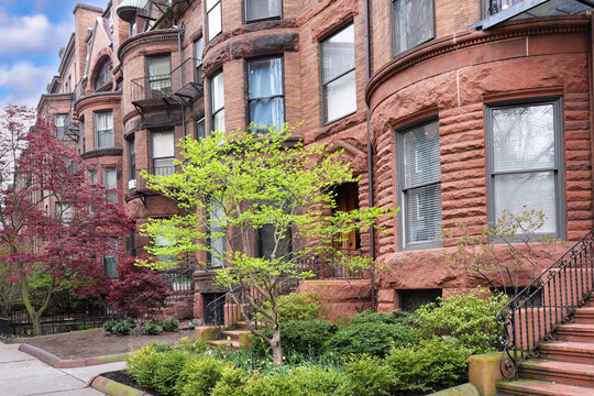 Long row of brownstone apartment buildings with bay windows