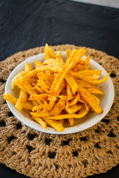 Deliciosas papas fritas crujientes con piment&oacute;n en taz&oacute;n blanco sobre un mantel r&uacute;stico de yute y fondo oscuro. Ideal para men&uacute; o snack.