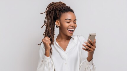 Fototapeta premium Excited young Black woman with dreadlocks celebrating success while looking at her smartphone screen with joy