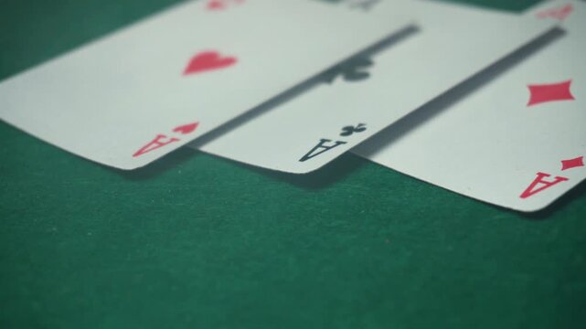 Playing cards with aces are arranged on a green felt surface, emphasizing their distinctive design and colors. Cigarette smoke above the poker table