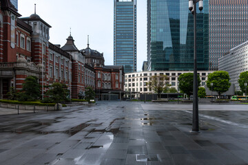 Naklejka premium Rainy Tokyo Station Marunouchi Plaza with reflections on wet pavement, modern skyscrapers and historic building, urban cityscape Japan 雨上がりの東京駅丸の内広場と濡れた路面の反射 高層ビルと歴史建築の都市景観