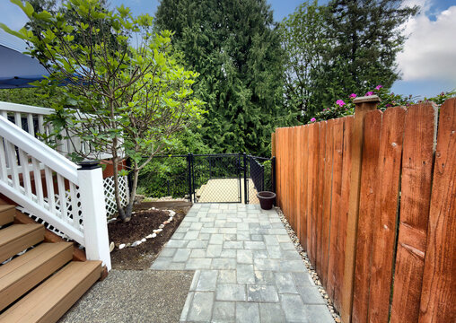 Stone pave pathway to lower deck of residential home with patio deck backyard and garden