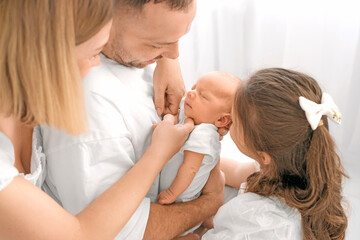 Fototapeta premium A newborn boy surrounded by loving parents. The family admires the baby, gently holding him in their arms.