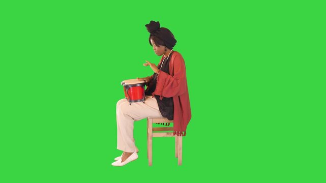 Concentrated african american woman tries to play bongos on a Green Screen, Chroma Key.