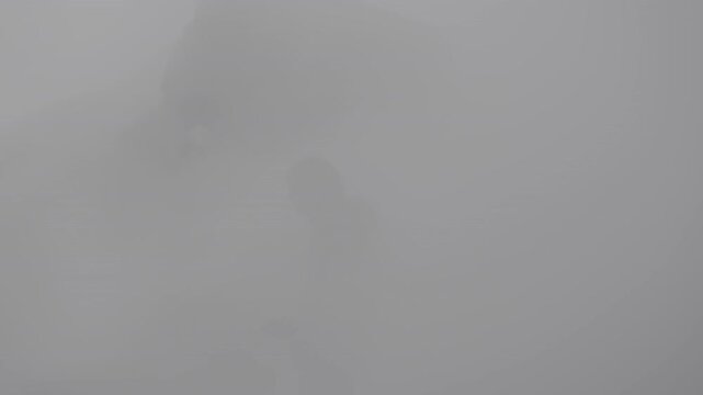 Silhouette of man in thick smoke who descended into crater with active volcanic activity. Extreme adventure concept. Slow motion 