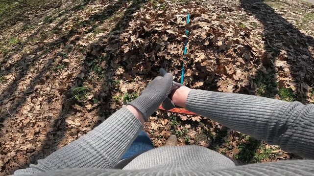 Gardener rakes dry oak leaves with a rake in the garden. First person view (POV). Spring or autumn cleaning of the garden. The process of raking fallen leaves in the garden with an orange rake. Work