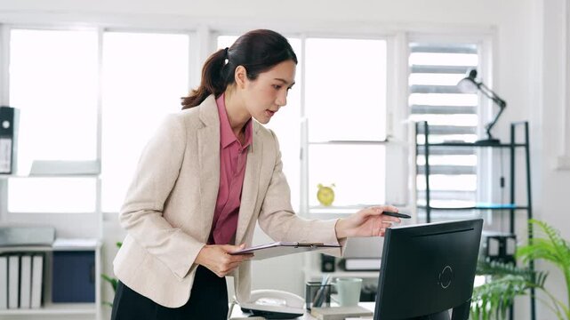 Young businesswoman hand holding pen taking notes , sitting at desk with laptop , analyzing information.