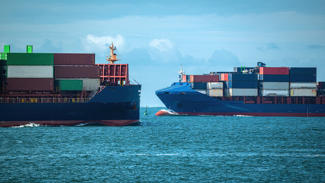 View of two large cargo container ships navigating the blue waters under a cloudy sky Lisbon, Lisbon, Portugal.