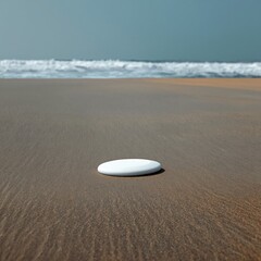 Obraz premium White Disc on Sandy Surface Under Clear Sky at Midday Near the Coast