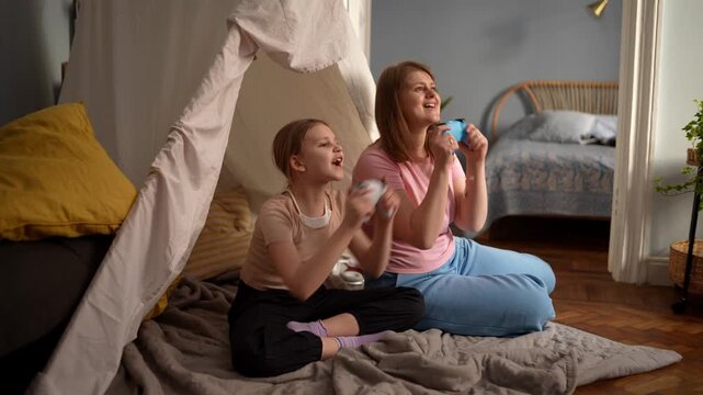 Cozy blanket fort with two sisters, pretend camp and storytelling, elder sister offering gentle hug, soft rug and pillows on wooden floor, warm lamp glow .