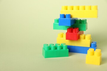 Naklejka premium Construction toy. Building blocks on pale green background, closeup. Space for text