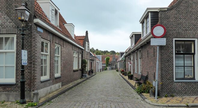 Quiet cobblestone street with brick houses and a no-entry sign