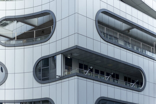 View of a modern building facade featuring unique rounded balcony openings and sleek grey panels in Taipei City, Taiwan.