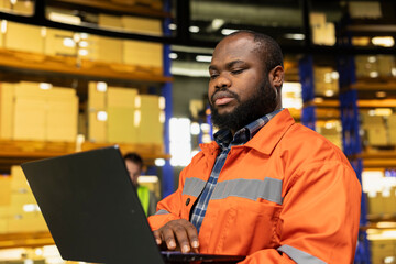 Fototapeta premium Black man verifying shipping details on laptop in fulfillment center facility. Technology tracking integrates with workflow planning to optimize parcel transportation and freight distribution.