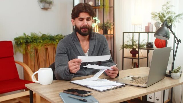 Indian man at home sees extra receipt feels annoyed throws paper aside shakes head shows dislike. Arabian guy at desk checks bill finds wrong charge gets angry plans claim to bank and cancels payment