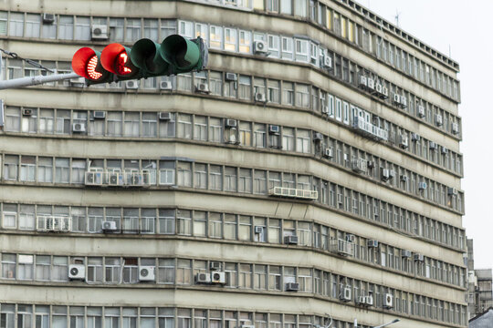 View of a red traffic light in front of a large residential building with numerous windows and air conditioning units Taipei City, Taiwan.