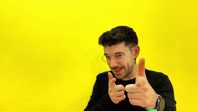Young surprised man pointing aside then smiling and gesturing at the camera