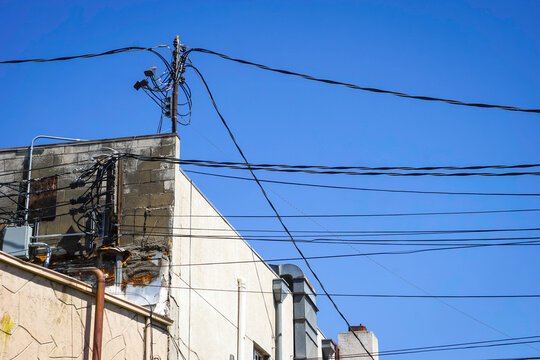 Old worn electrical power wires on urban building