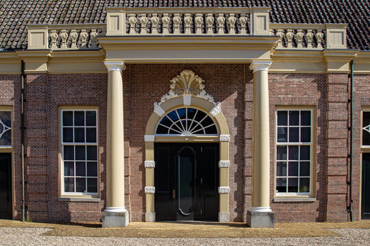 View of the grand entrance of Castle Groeneveld featuring a brick facade, elegant columns, and an arched doorway with ornate carvings in Baarn, Utrecht, Netherlands.