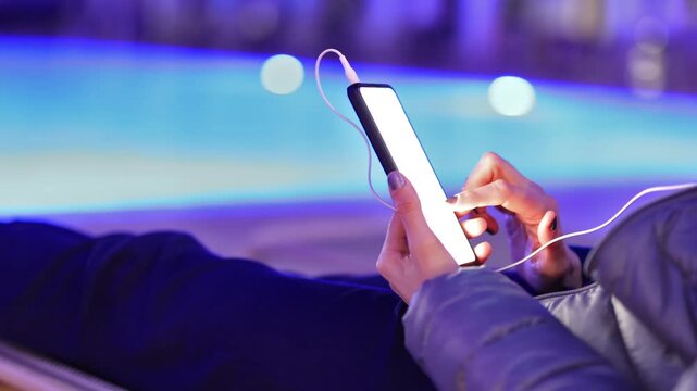 Woman using smartphone by pool at night &ndash; glowing screen, copy space, modern lifestyle.