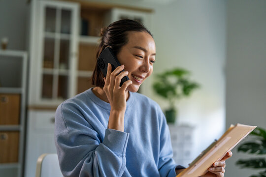 Asian woman remote working from home talking on phone