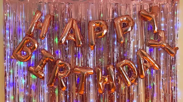 Happy Birthday balloon letters on shiny tinsel curtain background, festive party decoration celebration