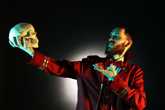Professional actor in suit with skull performing on black background with spotlight