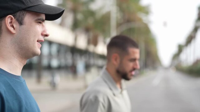 Two men walk side by side down a quiet street. One wears a cap, the other sports a beard. They look ahead, not at each other. Soft light bathes the palm-lined path