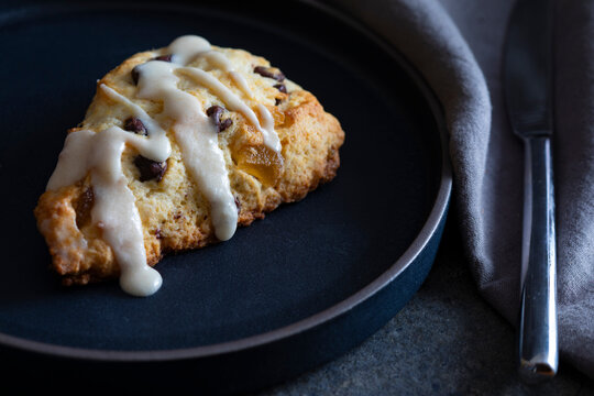 Scone with icing on dark plate