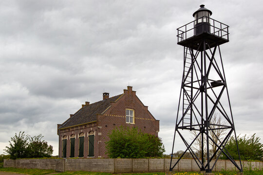 View of the historic Schokland lighthouse tower and the former church building under a cloudy sky in Schokland, Flevoland, Netherlands.