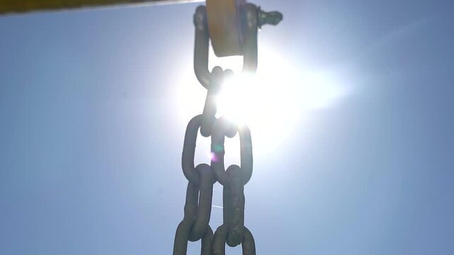 Industrial Chain Hanging Against Bright Sunlight with Lens Flare. Symbolizing unbreakable connections, resilience, and the invisible forces that hold everything together.