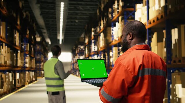Chroma key screen with black worker operating packages and cargo in warehouse facility, operational workflow and shipping activity assures order fulfillment operations for manual labor.