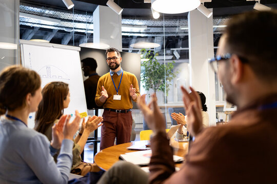 Business professional presenting ideas to colleagues, receiving applause during a corporate meeting or workshop