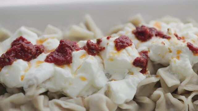 Close-up of traditional Turkish Manti with yogurt and red pepper sauce