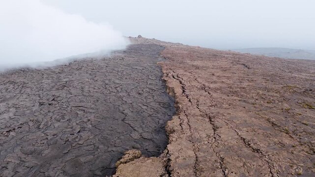 Aerial view of Erta Ale Volcano showing hardened lava flows and rising steam from the crater under a hazy sky in Danakil Desert, Afar, Ethiopia.