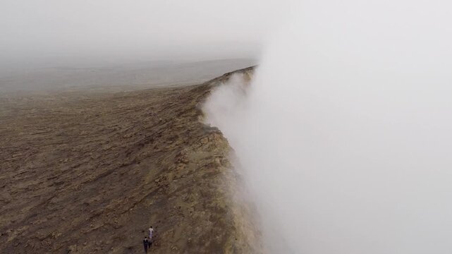 Aerial view of Erta Ale Volcano with people walking along the crater rim amidst thick volcanic steam in Danakil Desert, Afar, Ethiopia.