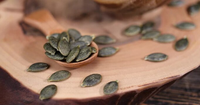green large pumpkin seeds are lying on a wooden walnut board and in wooden dishes, a large number of healthy large pumpkin seeds without shells are ready for cooking and eating