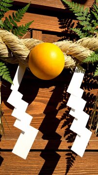 Traditional Japanese New Year Decoration Shimekazari with straw rope and orange on wooden door for cultural travel content and holiday celebrations Vertical. Video. Portrait Orientation.