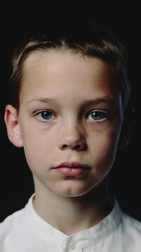 Young boy sticking out tongue against black background close up shot