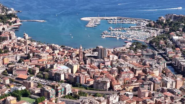 Aerial view of the coastal town of Rapallo featuring colorful buildings, a busy harbor filled with yachts, and the blue waters of the Mediterranean Sea Rapallo, Liguria, Italy.