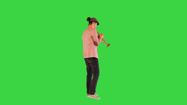 Young gifted street musician plays the trumpet masterly on a Green Screen, Chroma Key.